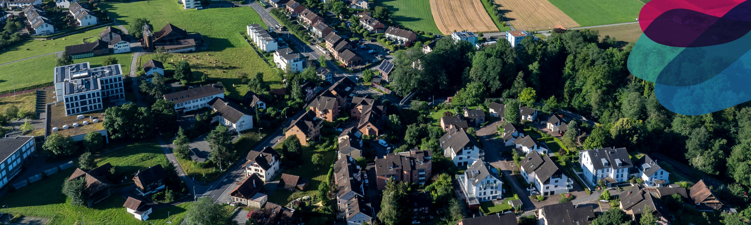 Luftaufnahme der Gemeinde H&uuml;nenberg. In einer Ecke &uuml;berlagern drei farbige Fl&auml;chen das Bild